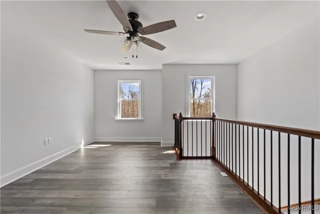 a view of empty room with wooden floor and fan