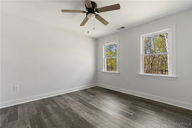 a view of an empty room and chandelier fan