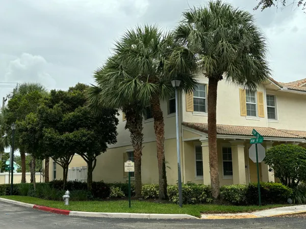 a front view of a house with a yard and palm trees