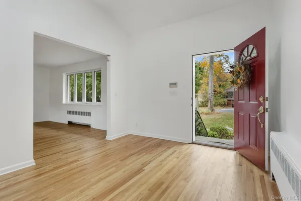 a view of an empty room with a window and wooden floor