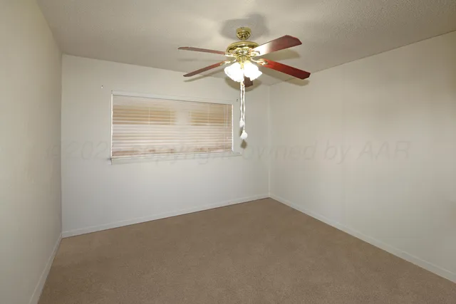 an empty room with a chandelier fan and windows