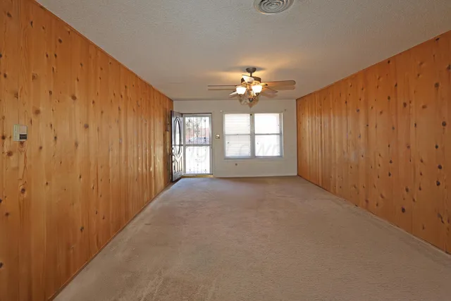 an empty room with windows chandelier fan and windows