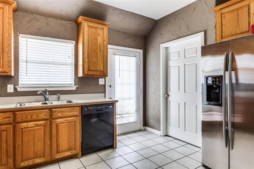 1008 Treys Court Sanger, TX 76266 - Photo 8 of 17 Kitchen featuring stainless steel refrigerator with ice dispenser, dishwasher, brown cabinets, and light tile patterned floors