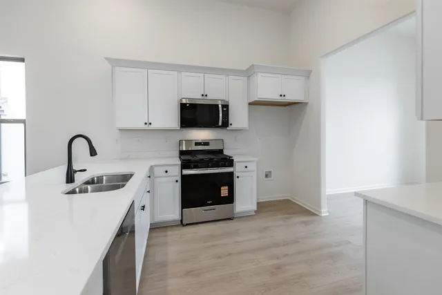 a kitchen with stainless steel appliances a stove a sink a microwave and cabinets