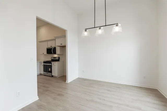 a view of kitchen and empty room with wooden floor