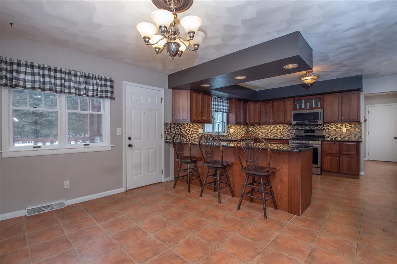 6526 North Marrill Road Byron, IL 61010 - Photo 9 of 25 a open kitchen with stainless steel appliances granite countertop a stove a refrigerator a sink a dining table and chairs with wooden floor