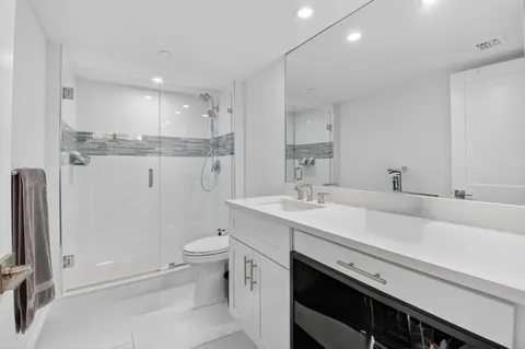 a bathroom with a shower sink vanity mirror and toilet
