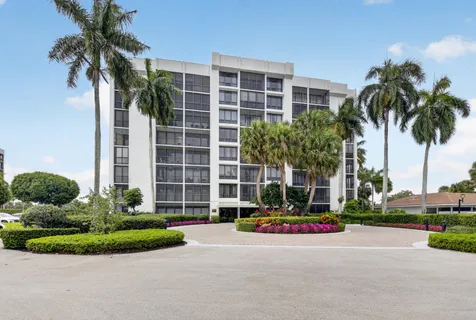 a front view of multi story residential apartment building with yard and green space