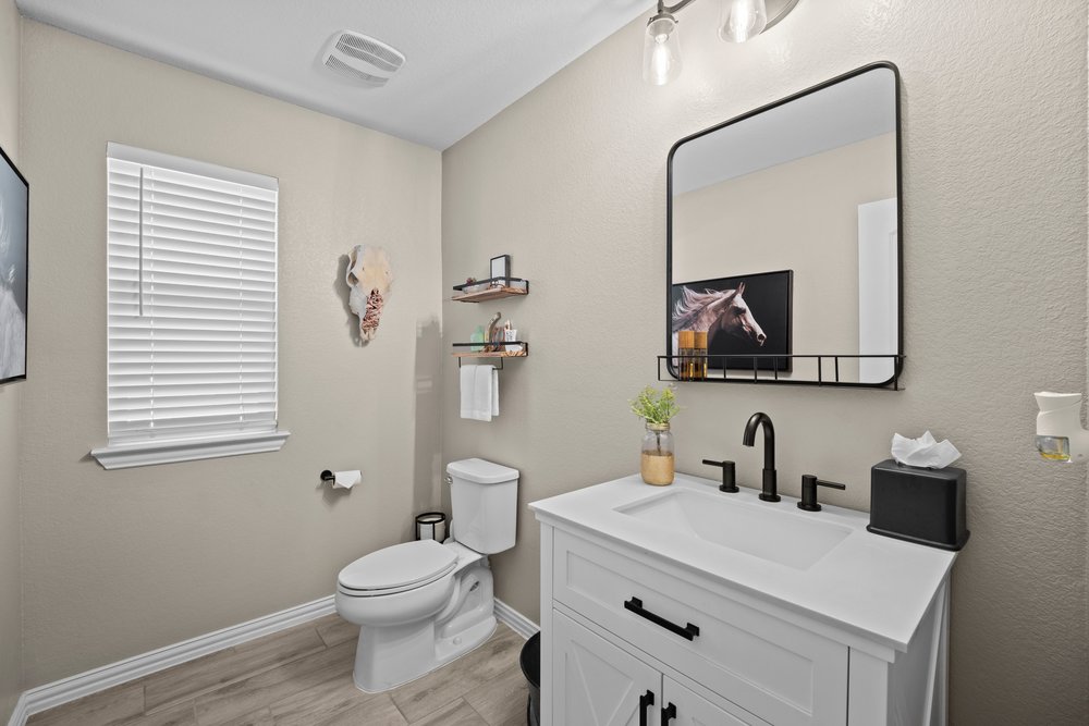 529 Cold Riv Run Kyle, TX 78640 - Photo 19 of 39 Guest bathroom features a farmhouse vanity with stand-alone mirror, ghost shelving, and wood look tile flooring.