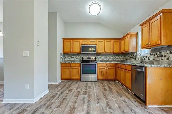 a kitchen with stainless steel appliances granite countertop a stove a sink and a microwave