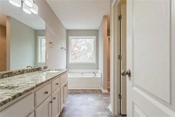 a spacious bathroom with a granite countertop tub sink and mirror