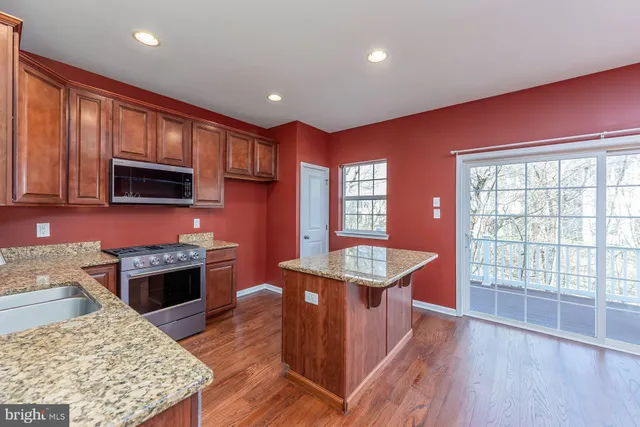 a kitchen with stainless steel appliances granite countertop a stove a sink dishwasher and a microwave oven with wooden floor