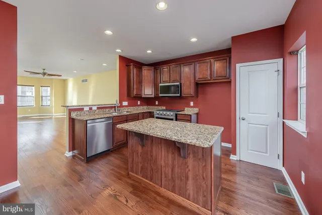 a kitchen with stainless steel appliances granite countertop a stove a sink dishwasher and a refrigerator with wooden floor