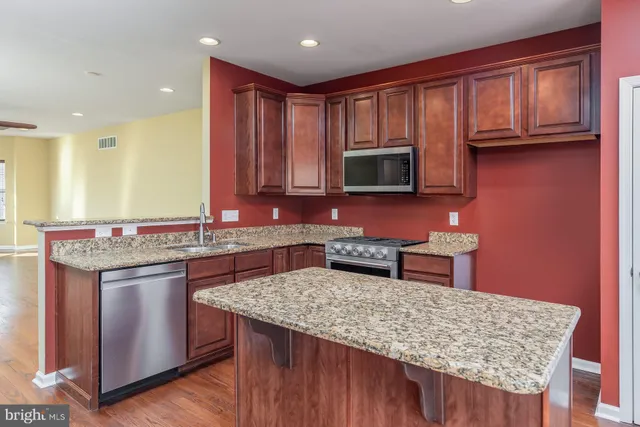 a kitchen with stainless steel appliances granite countertop a stove a sink and a microwave