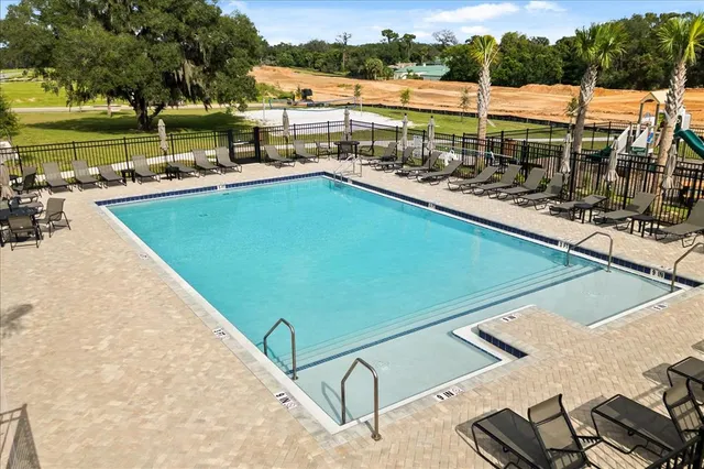 a view of a swimming pool with a patio and a yard