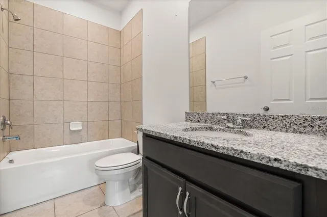a bathroom with a granite countertop sink a toilet and bathtub