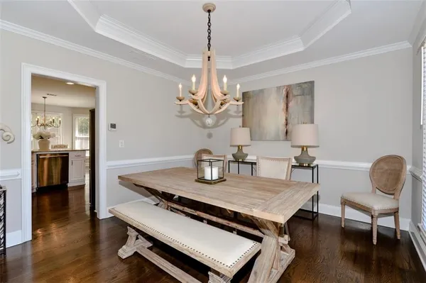 a dining room with wooden floor a chandelier a wooden table and chairs