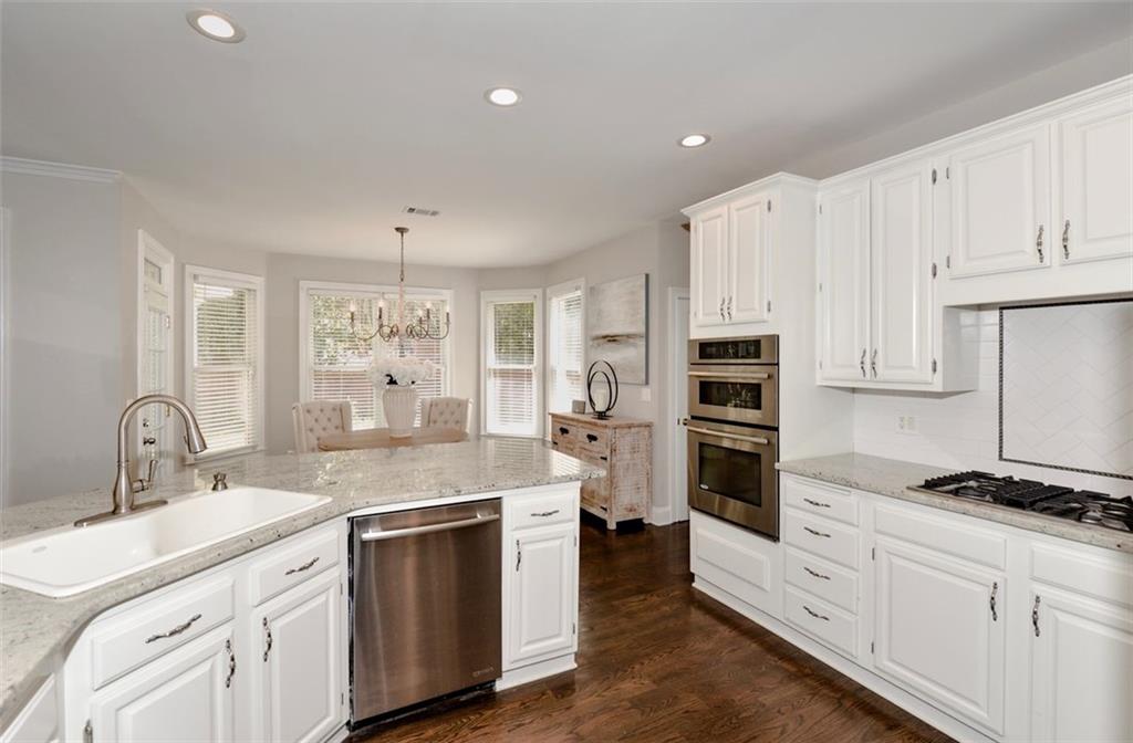 310 Windsor Gate Cove Northeast Atlanta, GA 30342 - Photo 19 of 58 a kitchen with granite countertop a sink stainless steel appliances and white cabinets