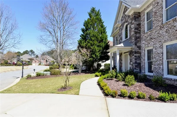 a front view of a building with garden and trees