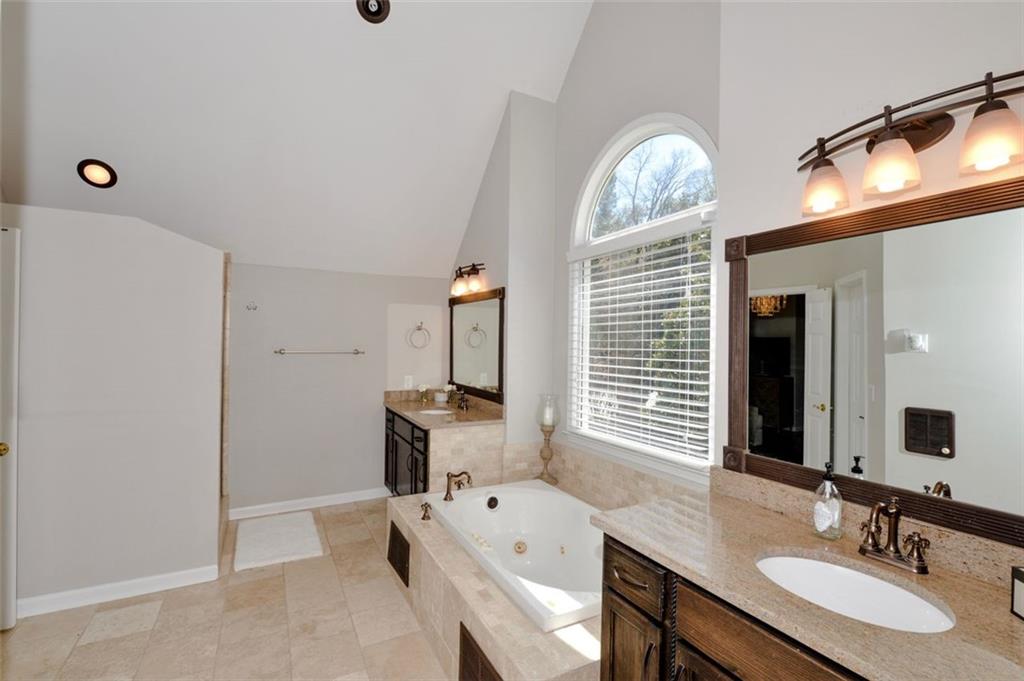 310 Windsor Gate Cove Northeast Atlanta, GA 30342 - Photo 41 of 58 a spacious bathroom with a sink a large mirror and a bathtub