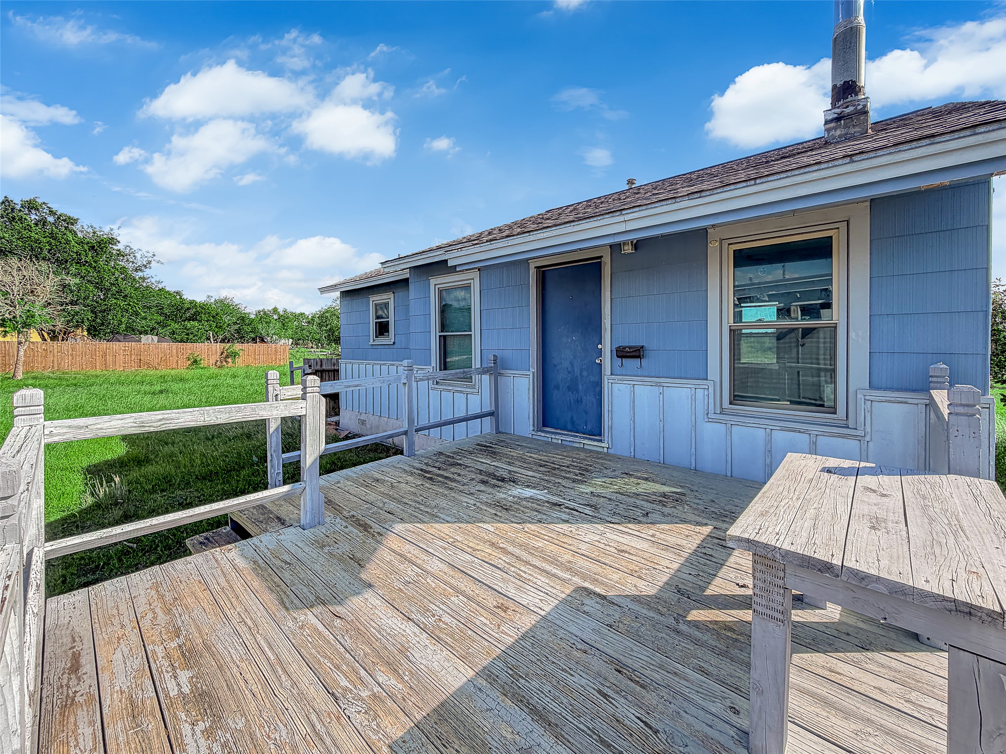 925 Long Hollow Road Dale, TX 78616 - Photo 16 of 21 An open wooden deck overlooks the grassy yard under a bright sky.