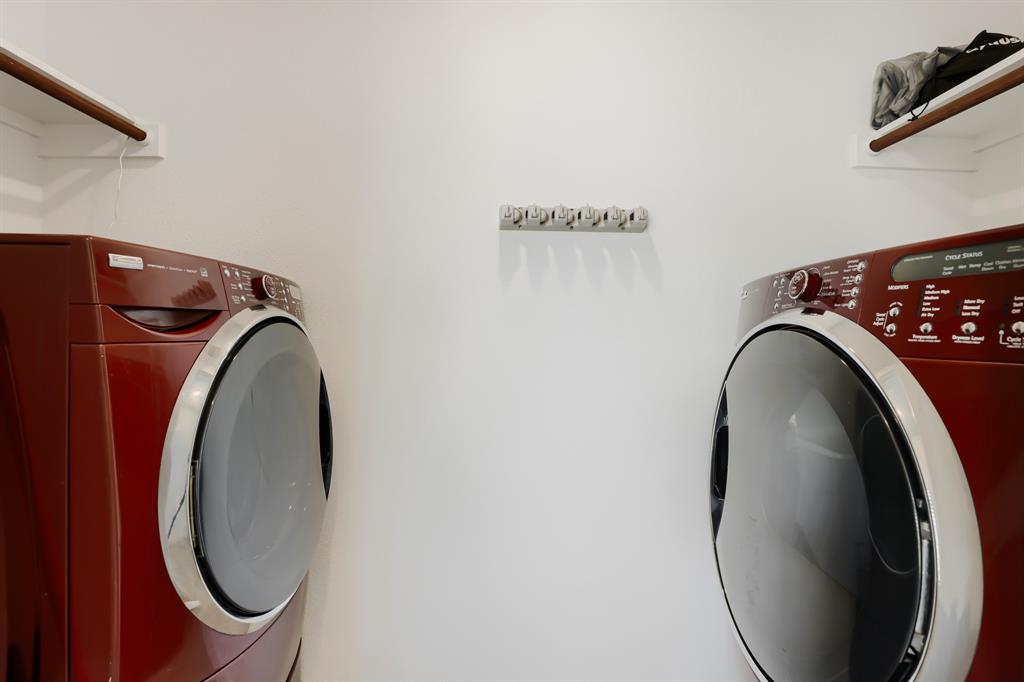 1619 Grassy Pond Road Forney, TX 75126 - Photo 26 of 28 Laundry area featuring a front-loading washer and dryer, wall-mounted drying rack, and wood-finish shelving