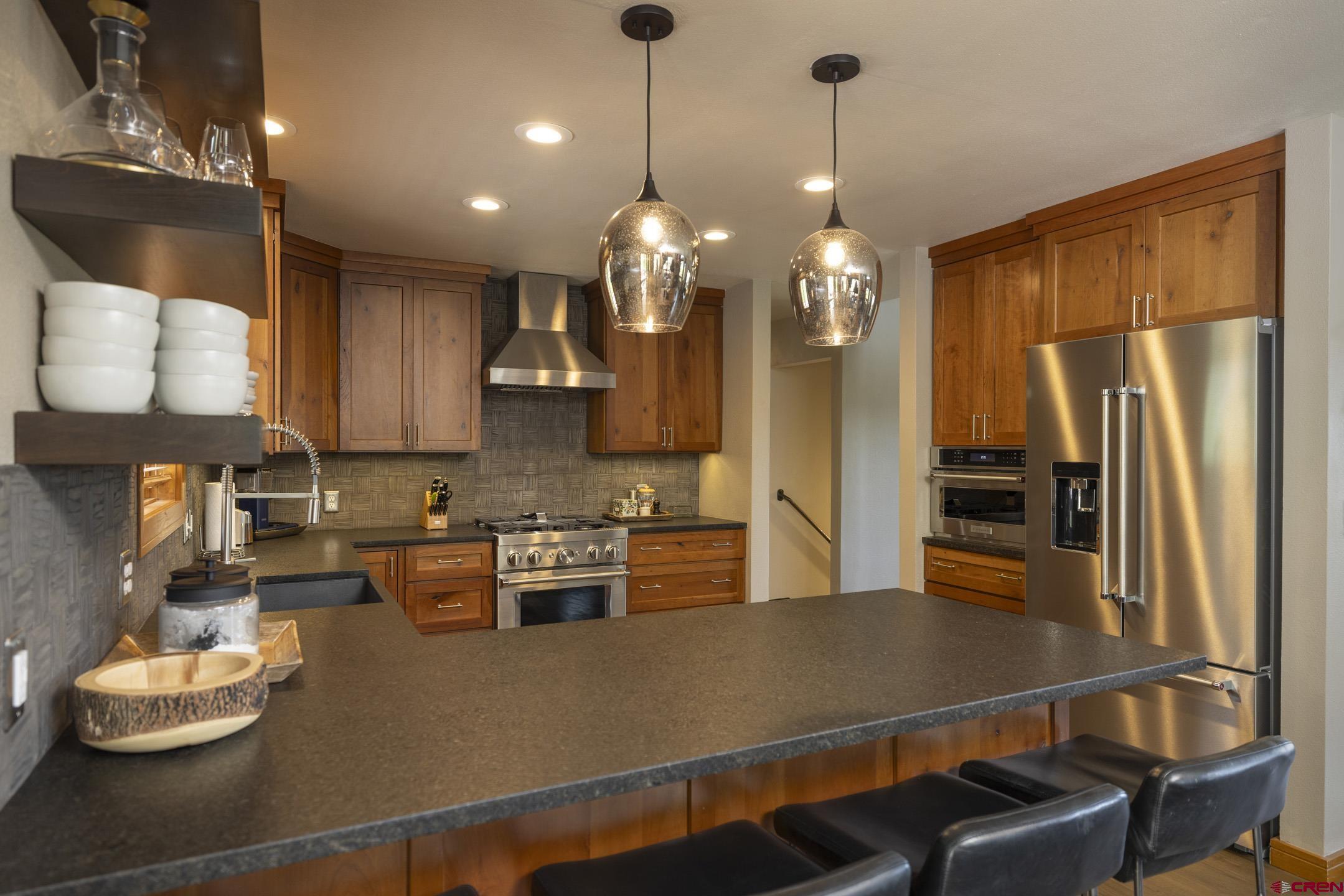 154 Falcon Ridge Road Durango, CO 81301 - Photo 17 of 42 a kitchen with stainless steel appliances granite countertop a refrigerator a sink dishwasher and a dining table with wooden floor