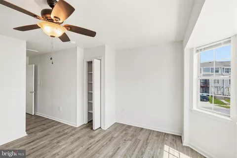 a view of an empty room with window and wooden floor