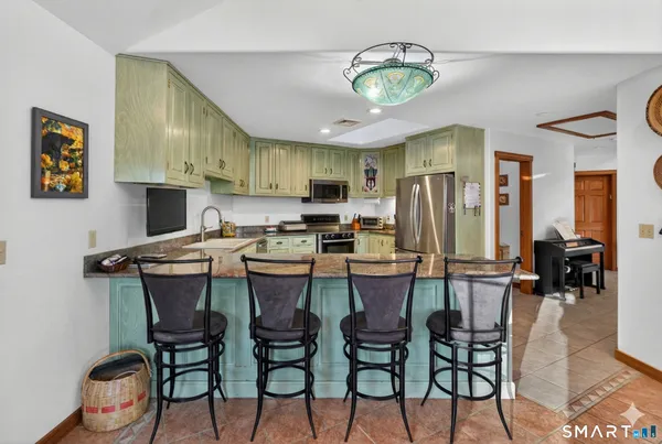 a kitchen with stainless steel appliances kitchen island granite countertop a table chairs and a refrigerator