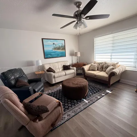 a living room with furniture ceiling fan and a window