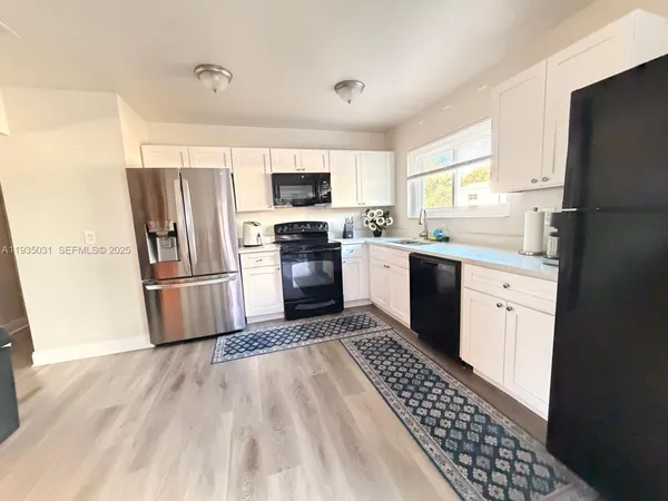 a kitchen with stainless steel appliances a refrigerator sink cabinets and wooden floor