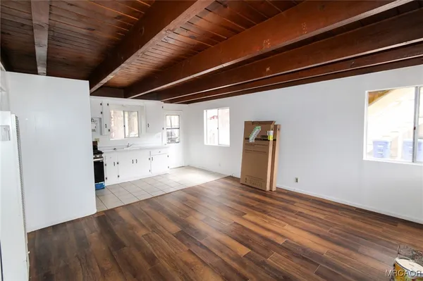 a view of an empty room with a window and wooden floor