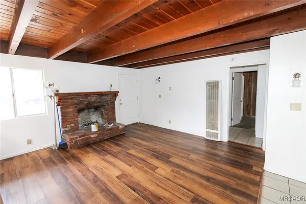 a view of empty room with wooden floor and fireplace