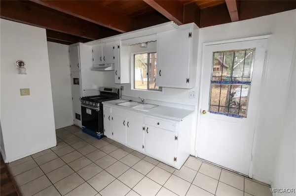 a kitchen with granite countertop a sink a stove and cabinets