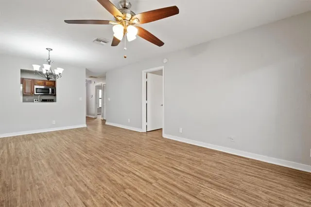 an empty room with wooden floor chandelier fan and closet area