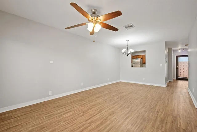 an empty room with wooden floor ceiling fan and windows