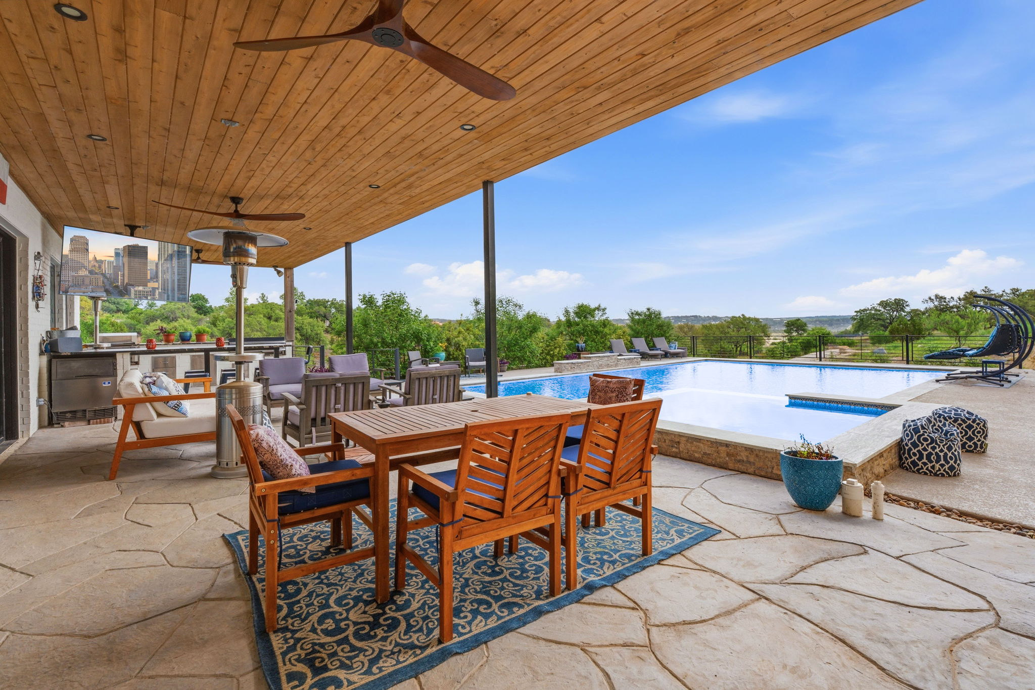 194 Placid Way Spring Branch, TX 78070 - Photo 32 of 37 Expansive outdoor living area featuring a covered patio with wood-finish ceiling and integrated fans, irregular flagstone paving, a built-in outdoor kitchen, and a large swimming pool