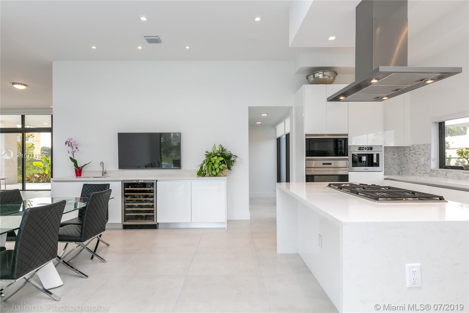 16630 Sunset Way Weston, FL 33326 - Photo 6 of 17 a kitchen with stainless steel appliances a stove a sink a microwave a refrigerator and white cabinets with wooden floor
