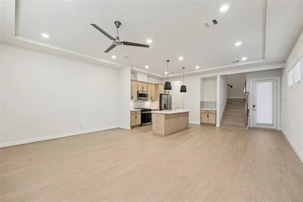 a view of an empty room with kitchen and a window