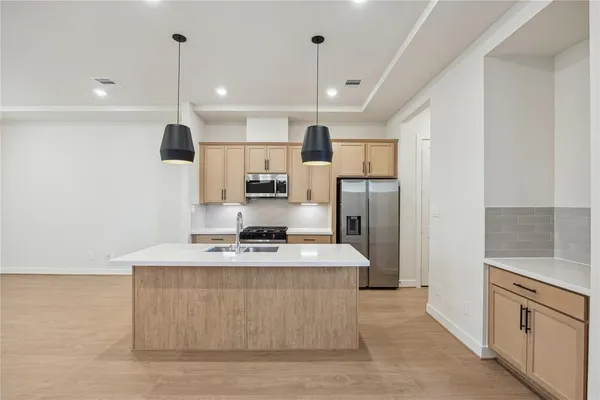 a large kitchen with stainless steel appliances kitchen island a stove a refrigerator a sink dishwasher a oven and a dining table with wooden floor