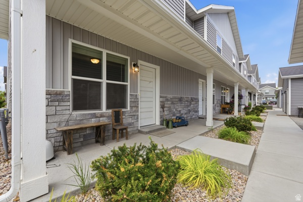 391 South 440th Street West Preston, ID 83263 - Photo 1 of 28 Exterior featuring gray vertical siding, stone veneer accents, white trim, a covered porch, and mature landscaping