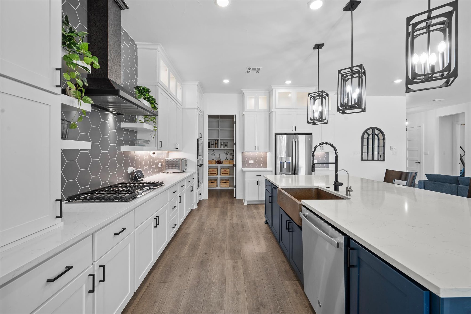 638 Strada Luca Florence, TX 76527 - Photo 11 of 38 This kitchen showcases a generous island, sleek modern appliances, and ample white cabinetry, all anchored by rich wooden flooring.