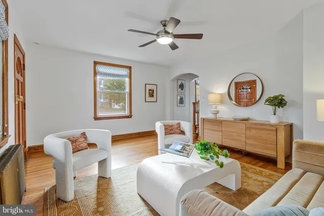 a living room with furniture a clock potted plant and a window