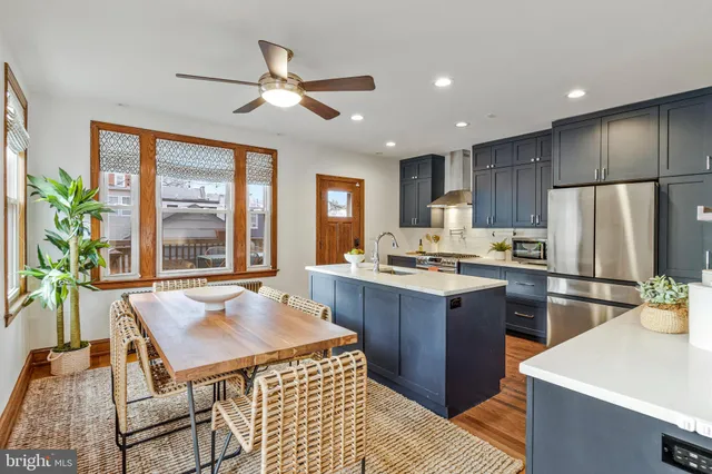 a kitchen with stainless steel appliances granite countertop a refrigerator a sink a stove a dining table and chairs