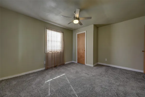 an empty room with windows and chandelier fan