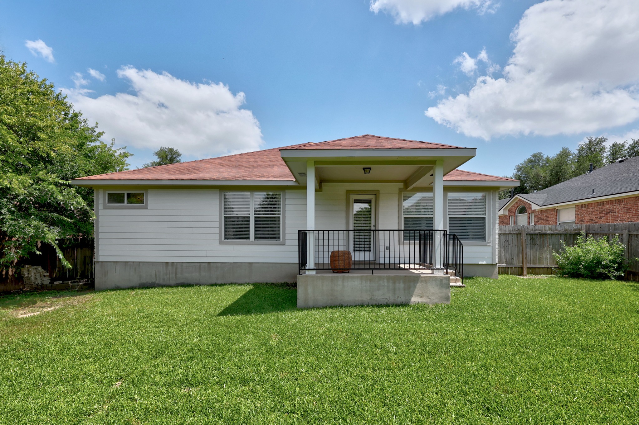 1108 Springbrook Road Pflugerville, TX 78660 - Photo 29 of 37 A well-maintained lawn stretches to meet the clean siding of this welcoming home, featuring a covered patio perfect for outdoor living.