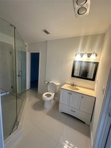a bathroom with a granite countertop sink mirror vanity and toilet