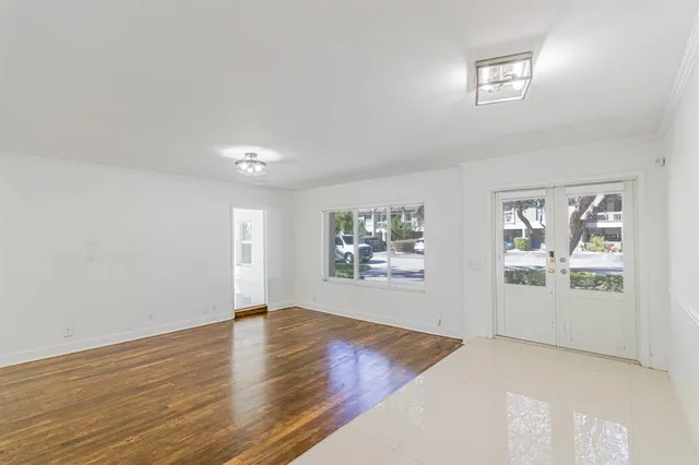 a view of an empty room with window and wooden floor