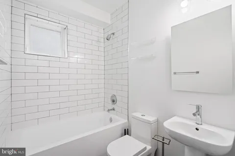 a bathroom with a bathtub shower sink mirror and toilet