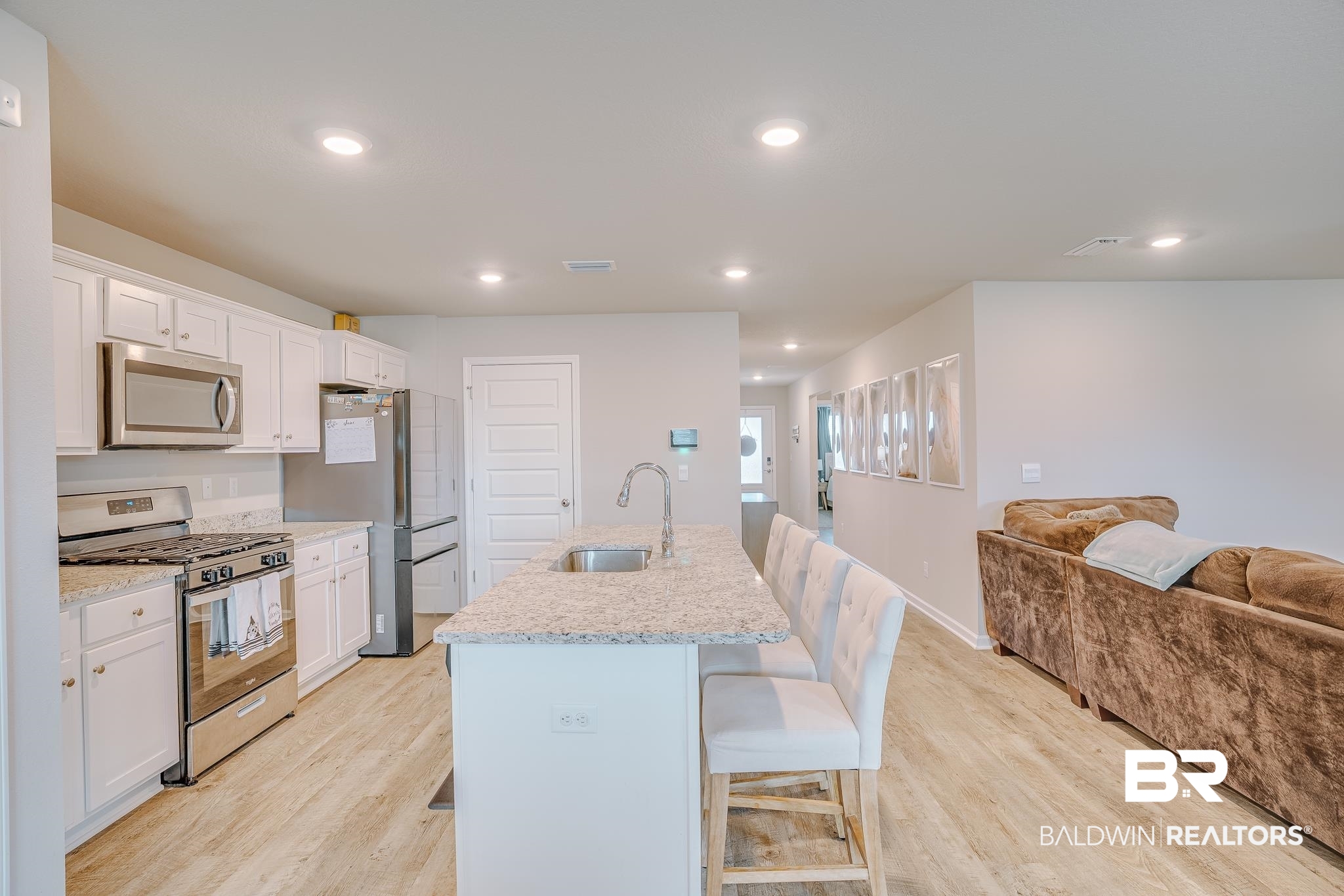 8242 Sycamore Way Semmes, AL 36575 - Photo 8 of 43 Kitchen featuring stainless steel appliances, a breakfast bar, light wood-style floors, white cabinetry, and recessed lighting